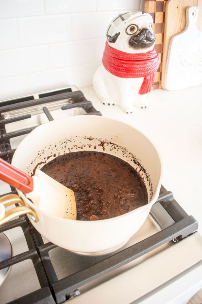 ingredients for homemade chocolate marshmallows being stirred with a spatula in a small pot on the stovetop.