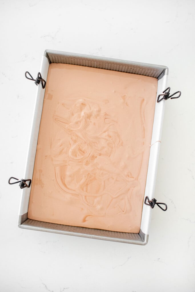 chocolate marshmallows in a 9x13 inch baking pan on a white marble counter.