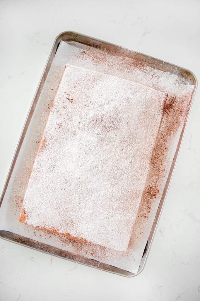 homemade chocolate marshmallows on a baking sheet with parchment paper with sifted powered sugar and cocoa on it.