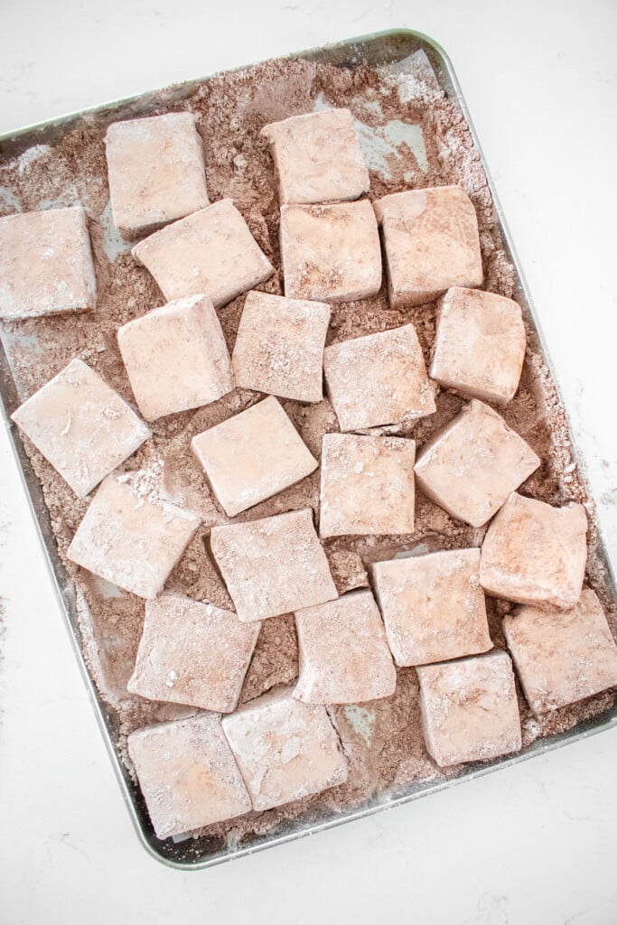 homemade chocolate marshmallows cut into large squares on a baking sheet on a marble counter.