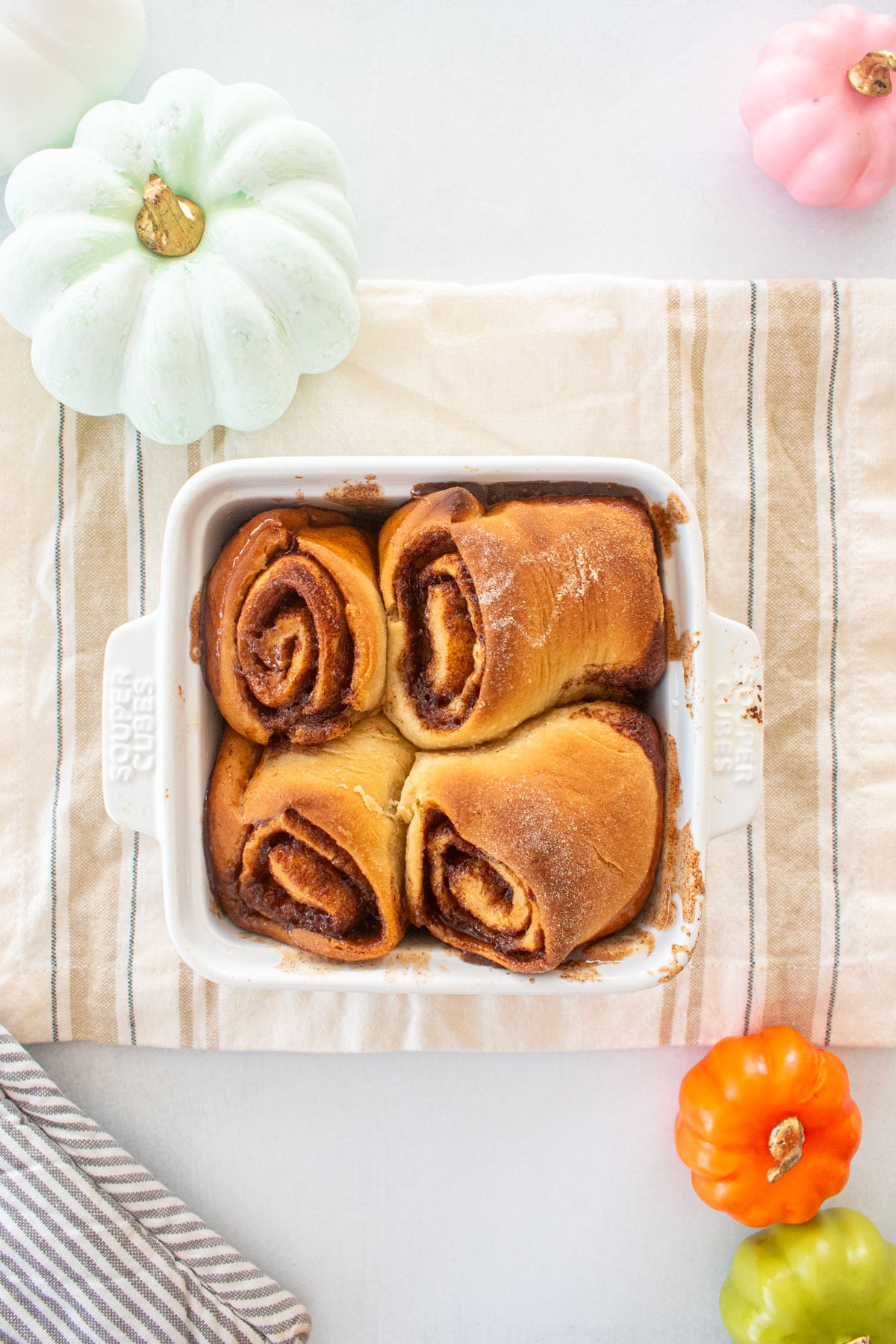 small batch honey butter cinnamon rolls in a white baking dish on a kitchen towel.