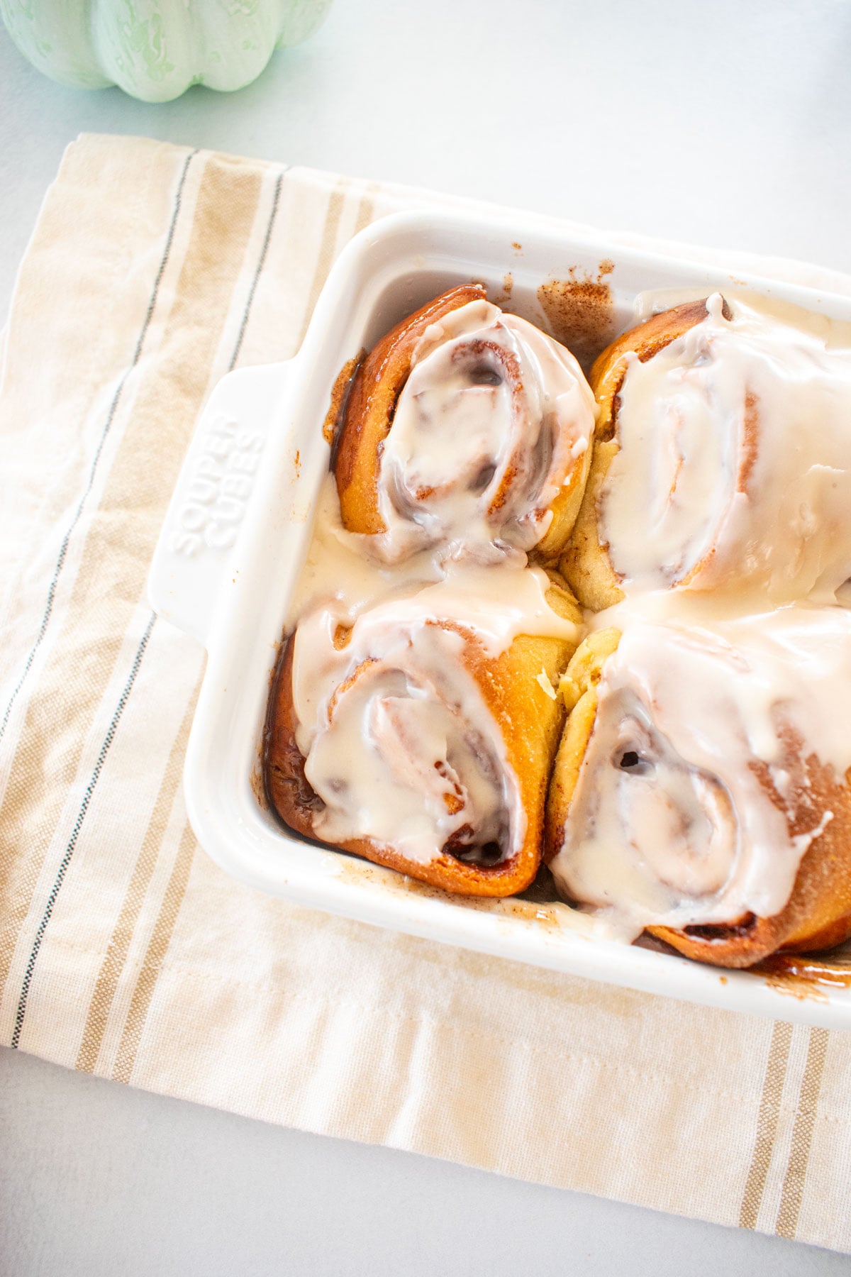 small batch honey butter cinnamon rolls in a white baking dish on a kitchen towel.