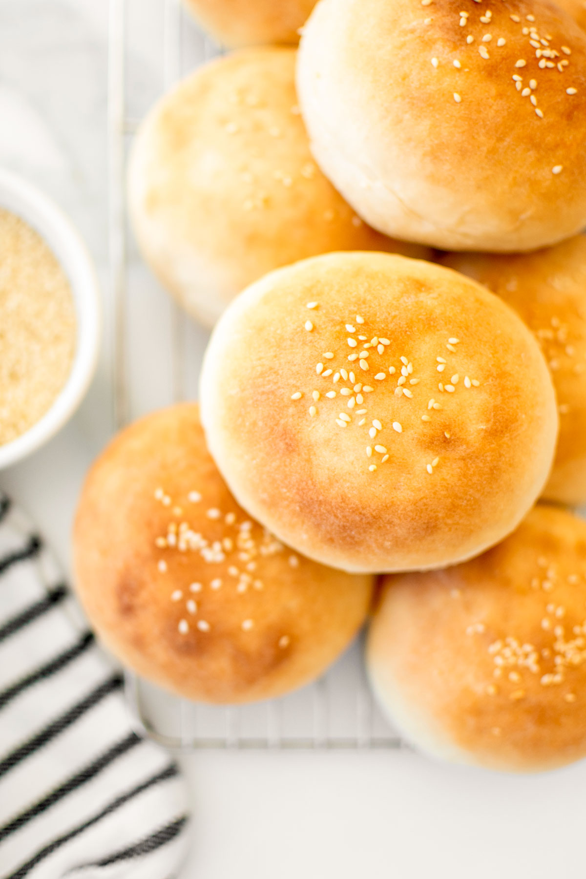 soft white hamburger buns on a cooling rack on a white marble counter.