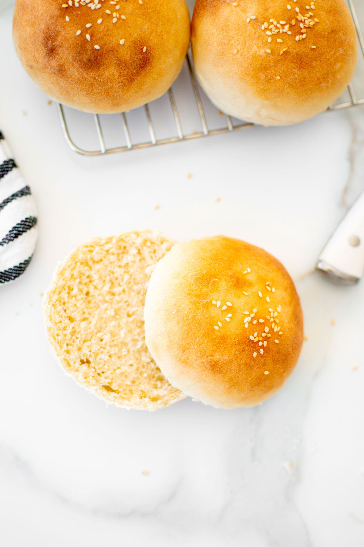 soft white hamburger bun sliced in half on a white marble counter.