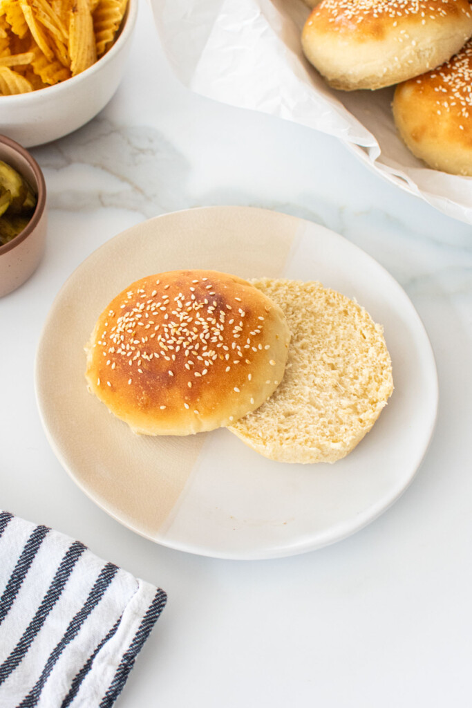 soft white hamburger bun sliced in half on a plate on a marble counter.