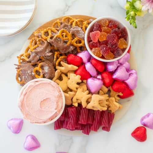 valentine's day charcuterie board on a white marble counter with fresh flowers.