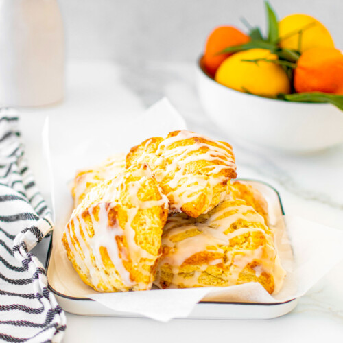 citrus scones on a platter on a white marble counter with fresh citrus in the background.