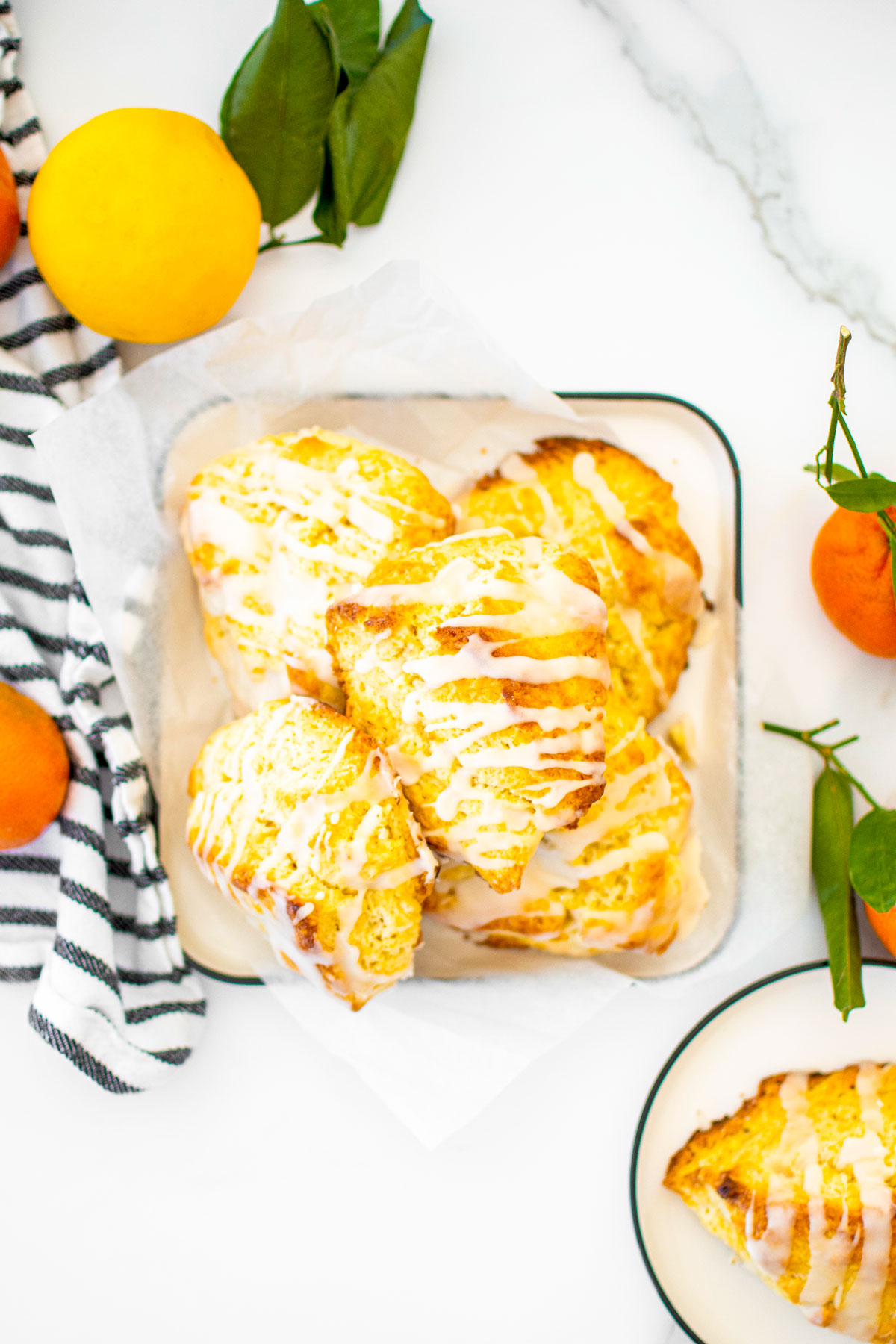 citrus scones on a platter on a white marble counter with fresh citrus in the background.