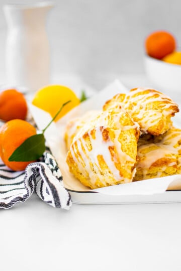 citrus scones on a platter on a white marble counter with fresh citrus in the background.