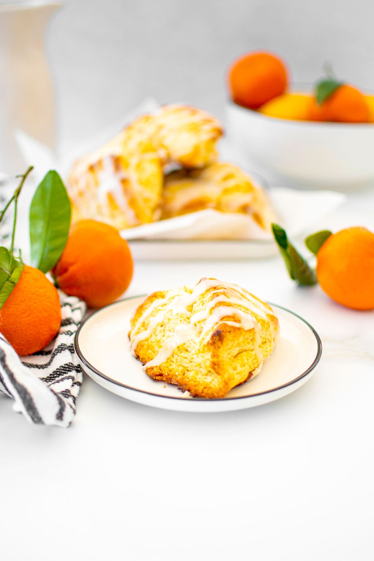 citrus scone on a white plate on a white marble counter with fresh citrus in the background.