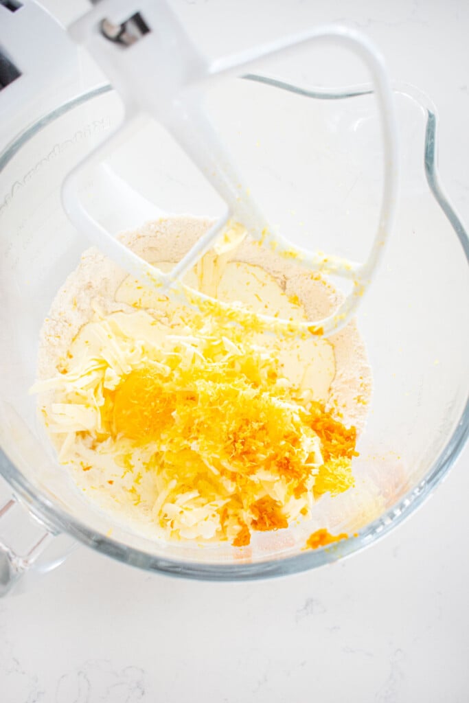 all ingredients for citrus scones in a glass mixing bowl on a white marble counter.