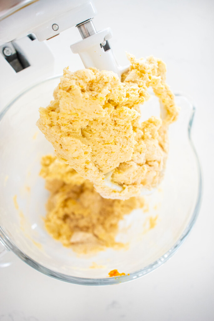 citrus scones dough in a glass mixing bowl on a white marble counter.