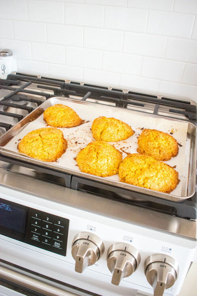 baked citrus scones on a baking sheet cooling on top of an oven.