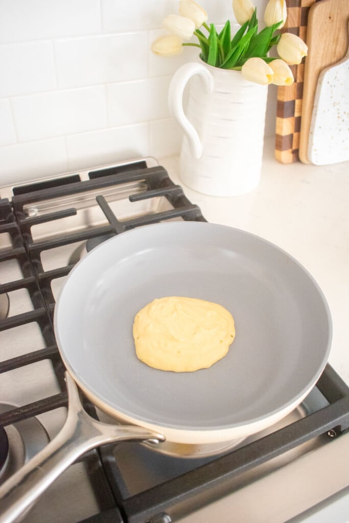 meyer lemon pancakes being cooked in a skillet on a stovetop.