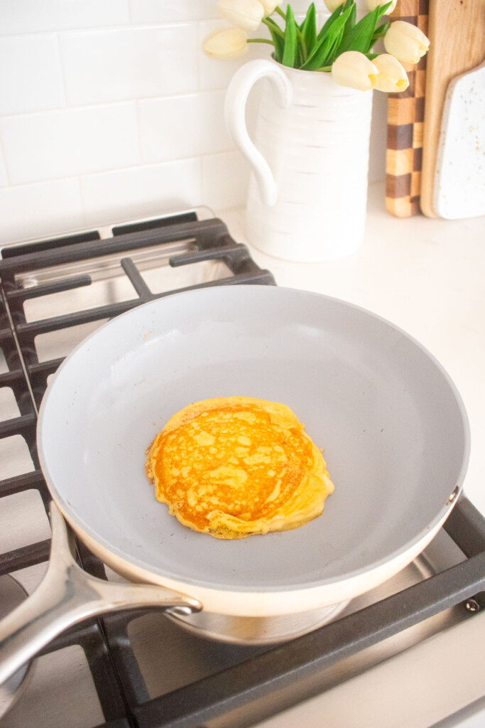 meyer lemon pancakes being cooked in a skillet on a stovetop.