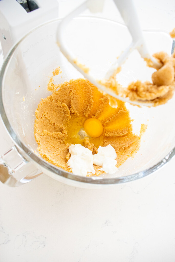 creamed butter and sugar in a glass stand mixing bowl with an egg and yogurt.