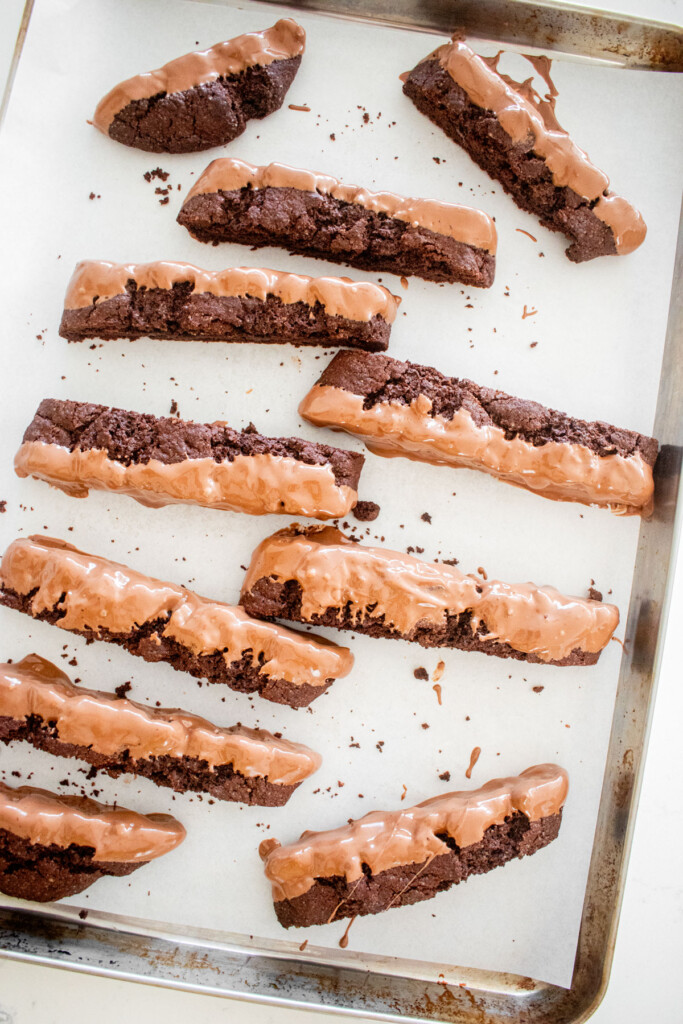 chocolate biscotti dipped in milk chocolate on a baking sheet.