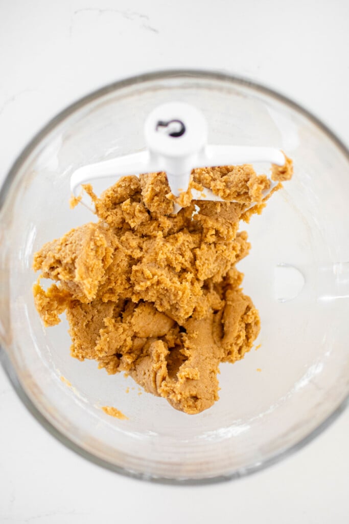 vegan banana cookie dough in a glass mixing bowl on a marble counter.