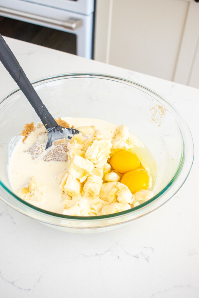 wet ingredients for almond butter banana bread in a glass bowl on a white marble counter.