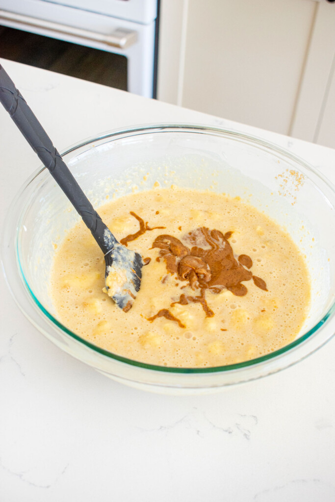 ingredients for almond butter banana bread in a glass bowl on a white marble counter.