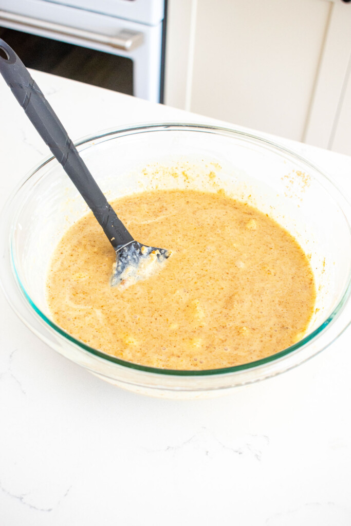 ingredients for almond butter banana bread in a glass bowl on a white marble counter.