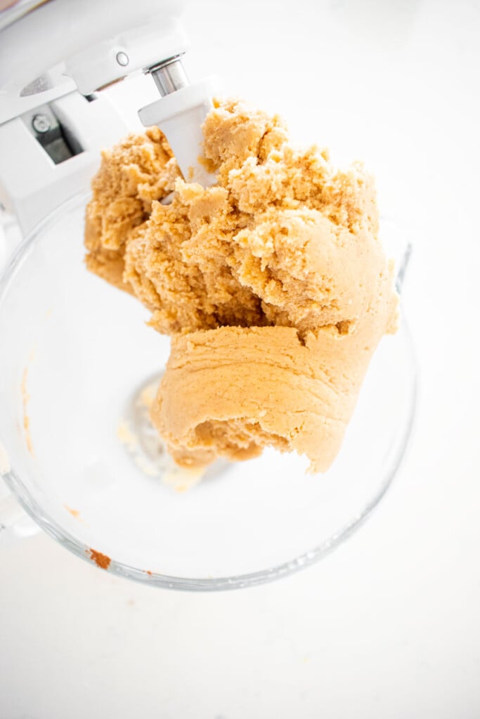cinnamon pecan greek butter cookie dough in a glass stand mixing bowl on a white marble counter.