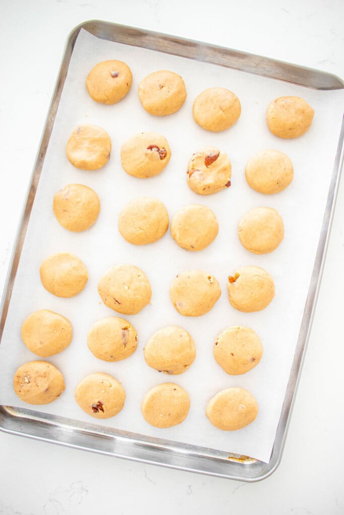 baking sheet with cookie dough balls on a white marble counter.