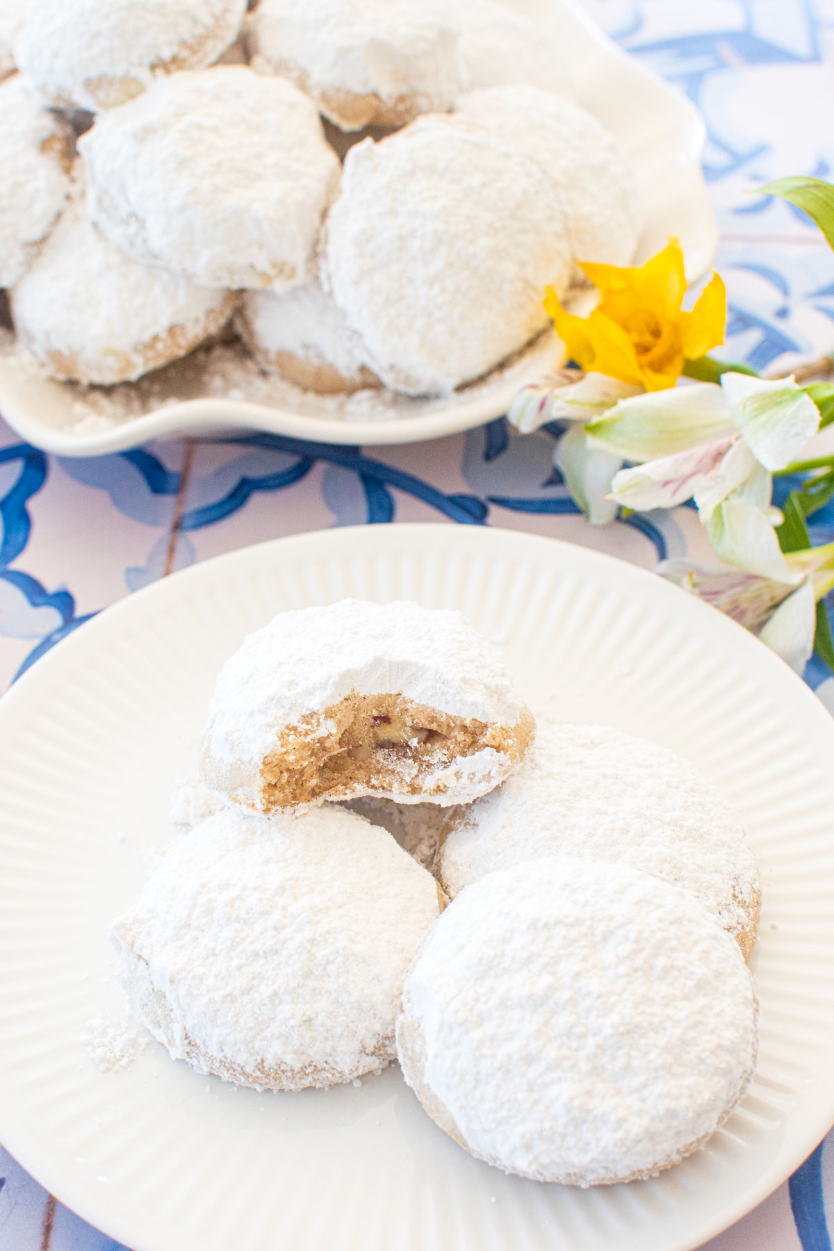 cinnamon pecan greek butter cookies on a dessert plate one with a bite taken out of it.