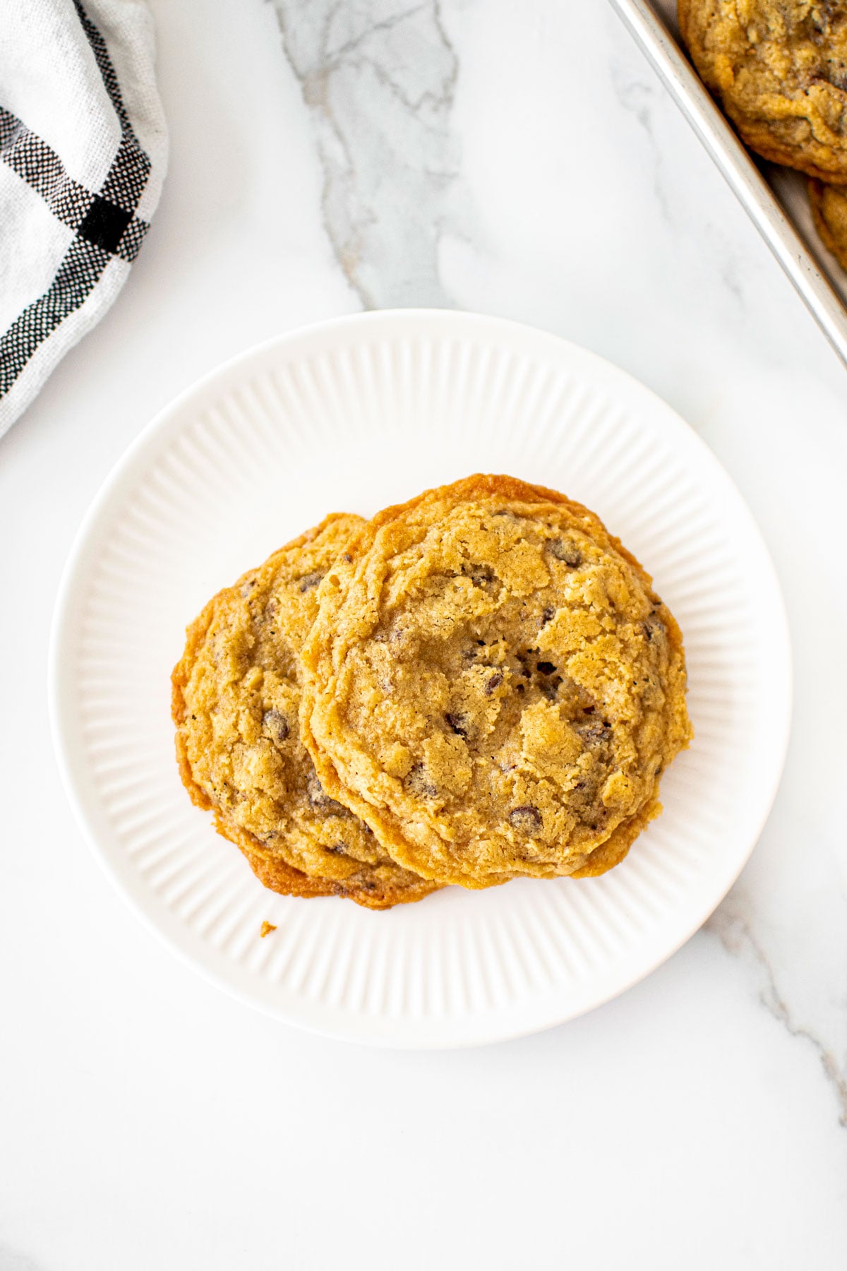 plate with two oatmeal cashew butter chocolate chip cookies on a marble counter.