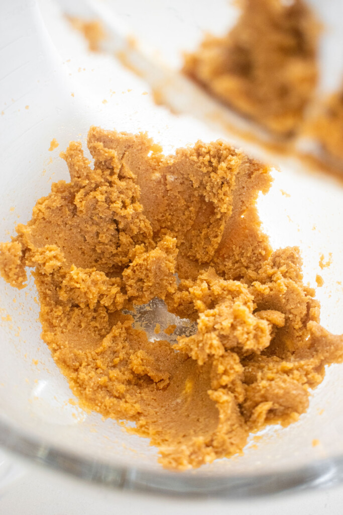 creamed light brown sugar and butter in a glass mixing bowl on a marble counter.