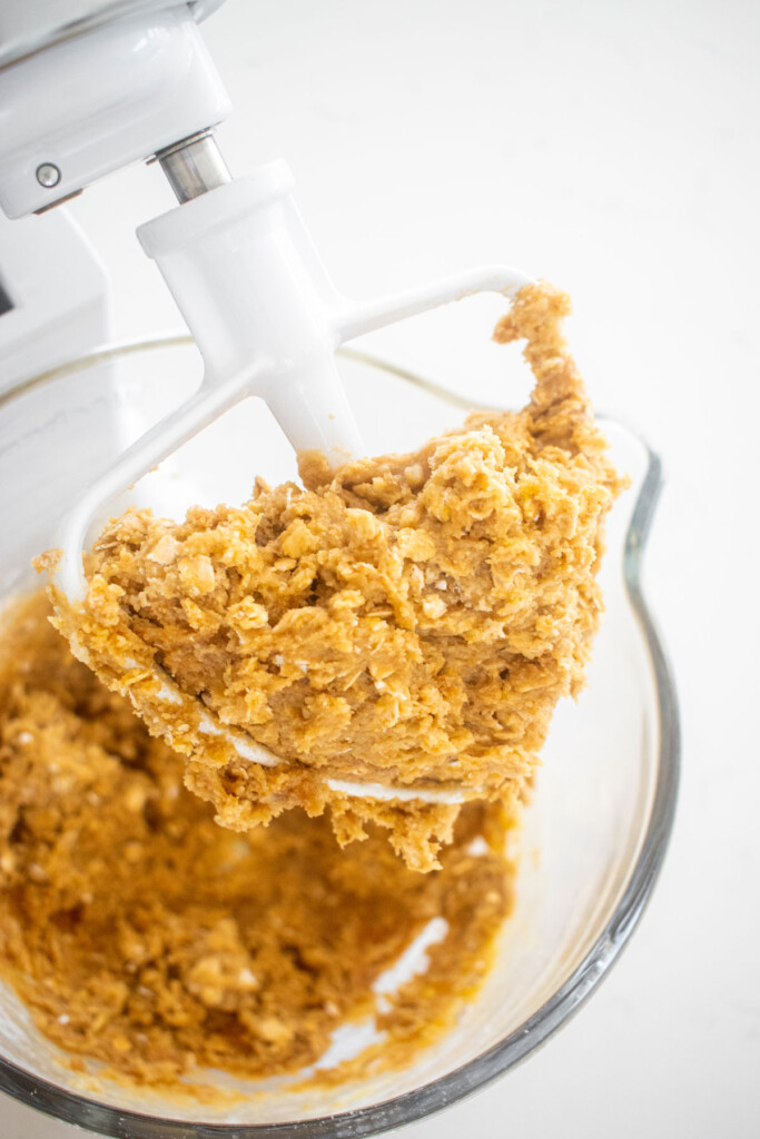 oatmeal cashew butter chocolate chip cookie dough in a glass mixing bowl on a marble counter.