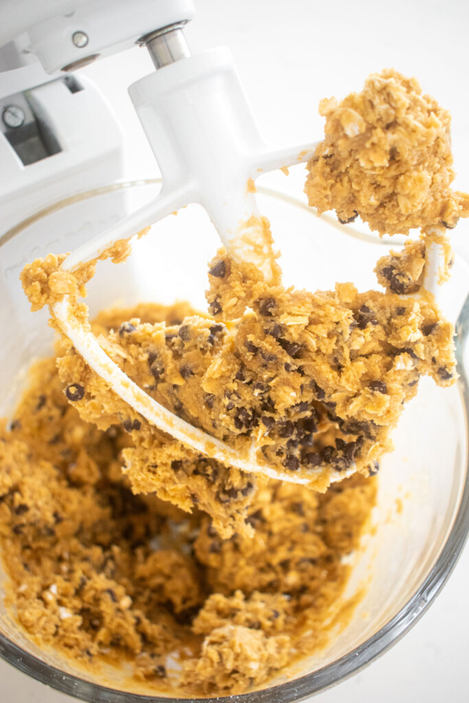 oatmeal cashew butter chocolate chip cookie dough in a glass mixing bowl on a marble counter.