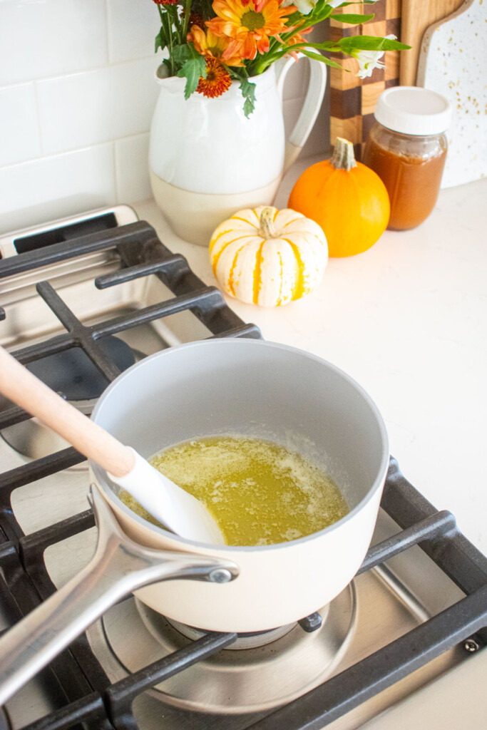 small pot with melted butter being stirred with a spatula on the stovetop.