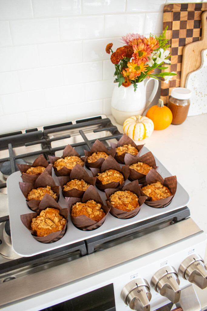 eggless banana raspberry muffins in a muffin pan cooling on top of an oven.