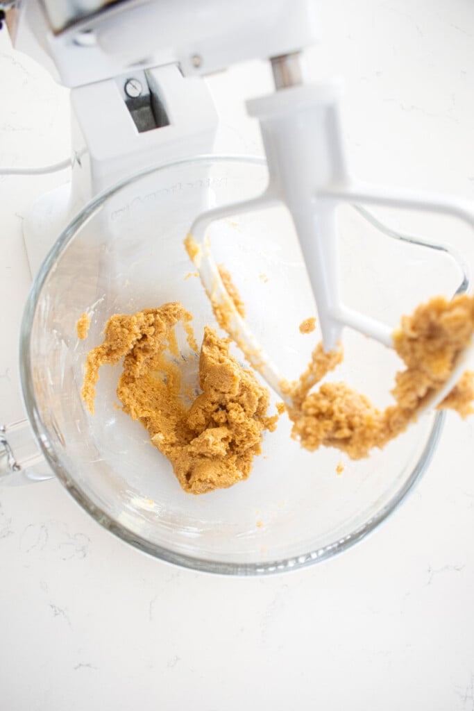 creamed butter and sugar in a glass mixing bowl on a white marble counter.