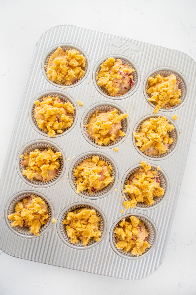 muffin pan with eggless banana raspberry muffins on a white marble counter.