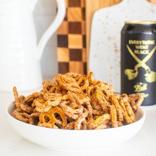 bowl of garlic ranch pretzels with white cheddar on a white marble counter with a beer.