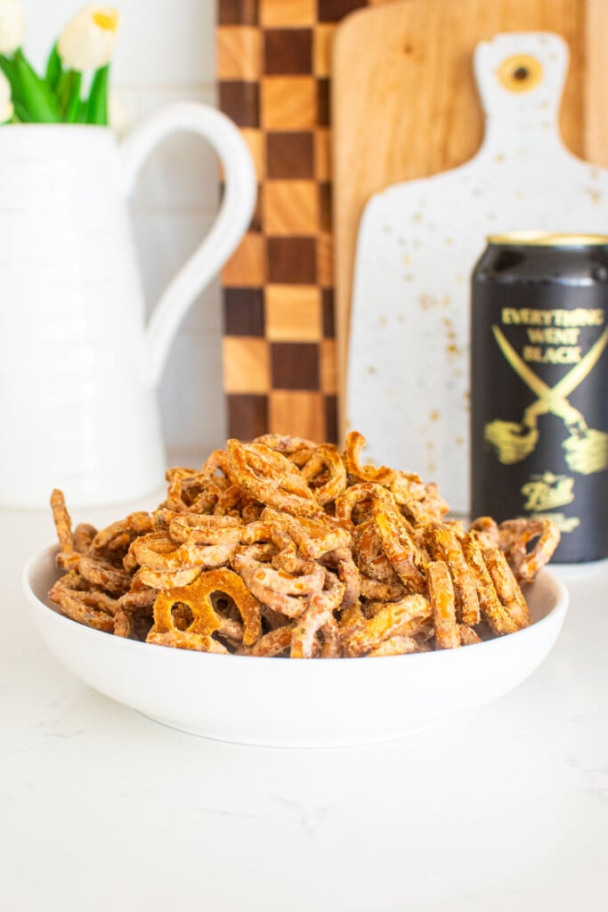 bowl of garlic ranch pretzels with white cheddar on a white marble counter with a beer.