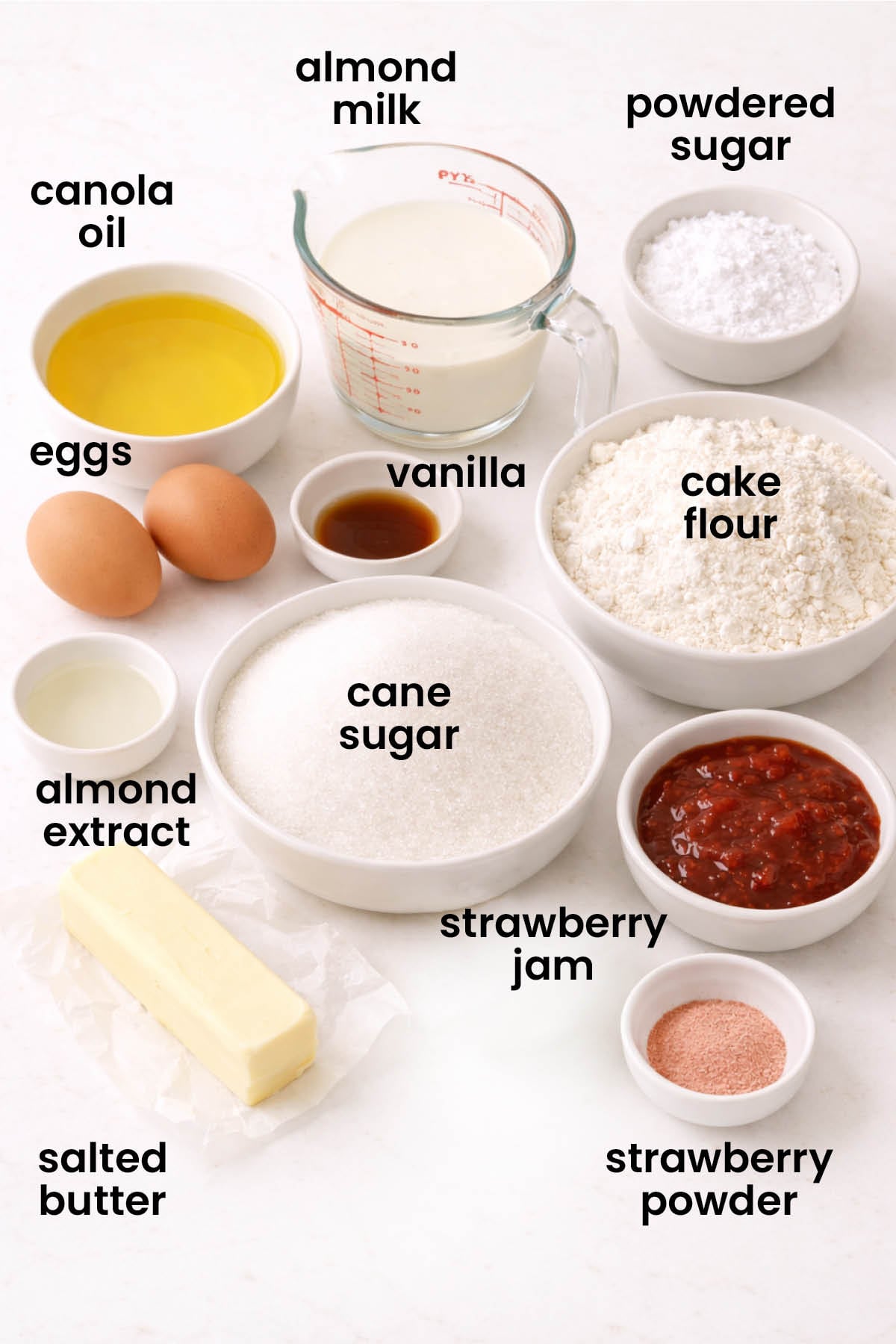 individual ingredients for strawberry almond cake laid out against a white background.