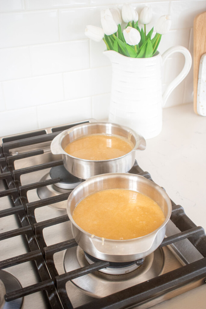 two 6-inch cake pans with almond cake batter on top of a stovetop.
