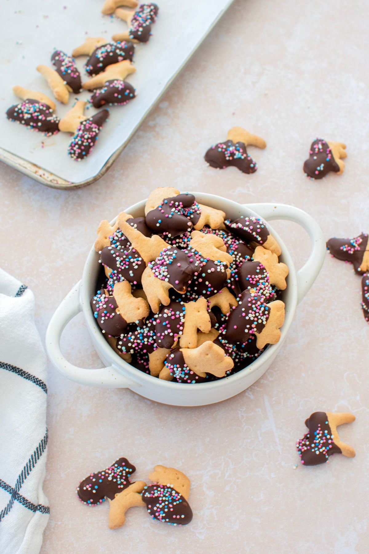 bowl of chocolate dipped animal crackers with sprinkles on a table.