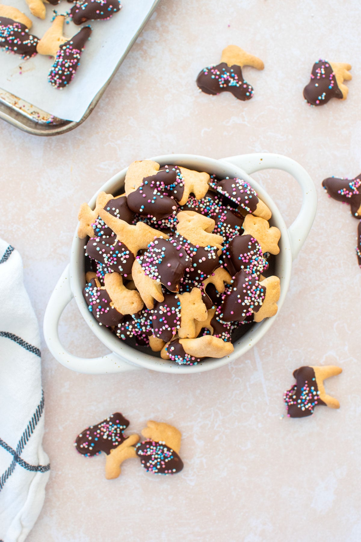 bowl of chocolate dipped animal crackers with sprinkles on a table.