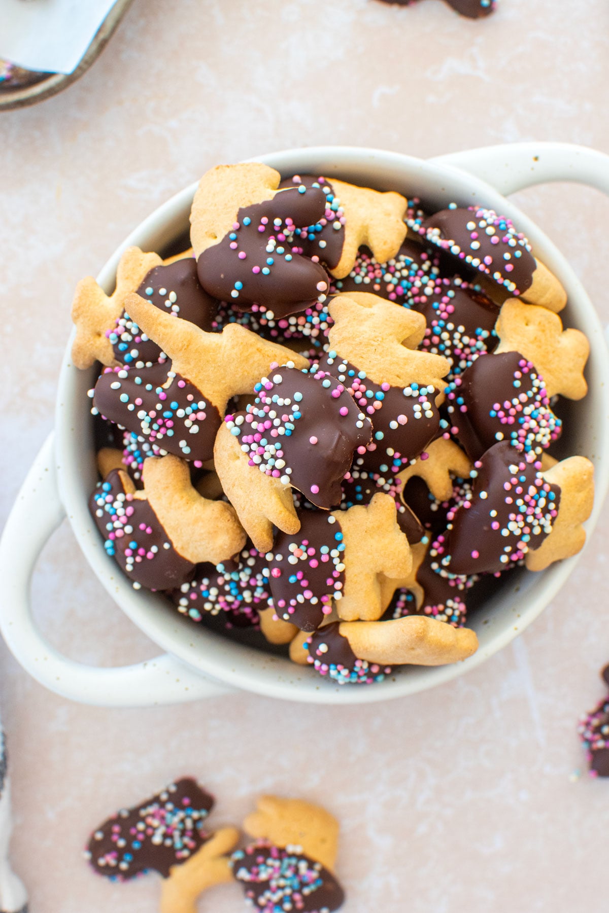 bowl of chocolate dipped animal crackers with sprinkles on a table.