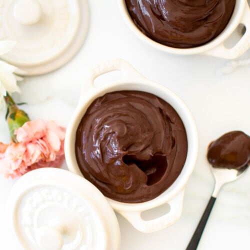 chocolate protein pudding with bone broth in small dutch ovens on a white marble counter with fresh flowers.
