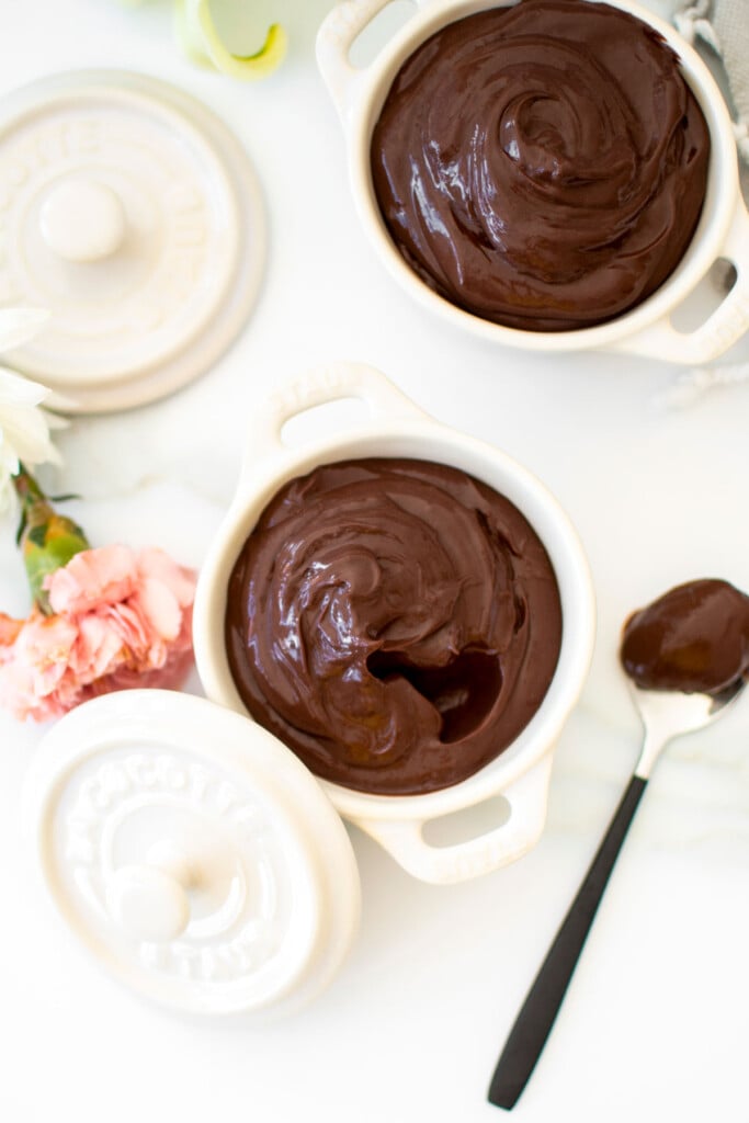 chocolate protein pudding with bone broth in small dutch ovens on a white marble counter with fresh flowers.