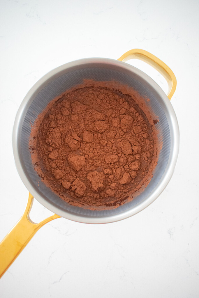 ingredients for chocolate protein pudding in a pot on a white marble counter.