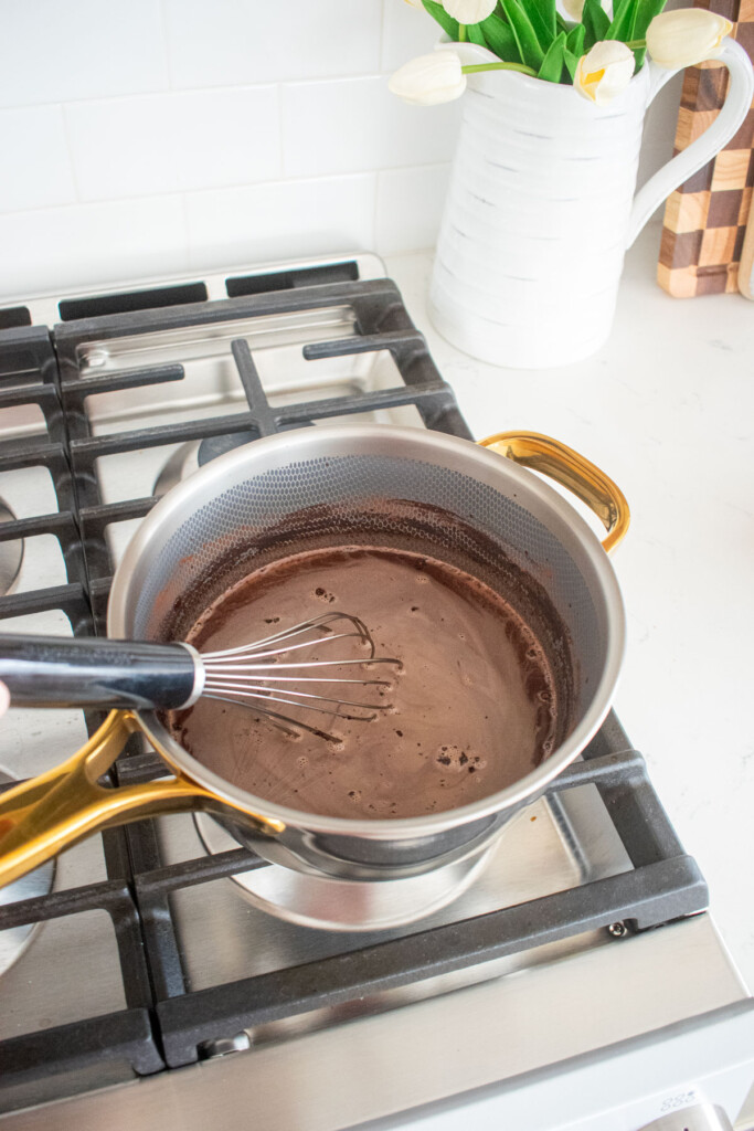chocolate protein pudding with bone broth being cooked in a small pot over the stovetop.