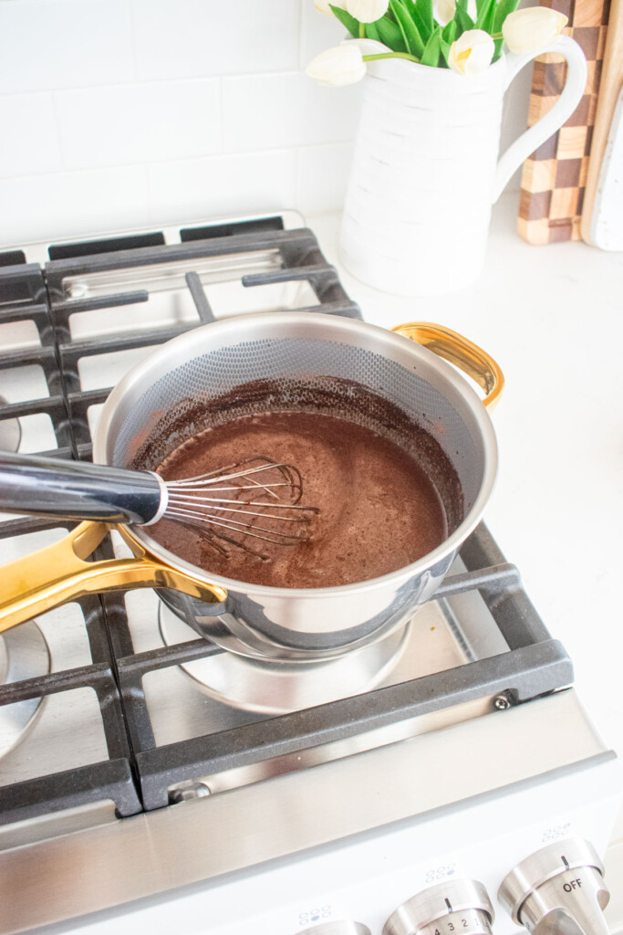 chocolate protein pudding with bone broth being cooked in a small pot over the stovetop.