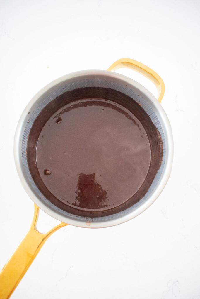 chocolate protein pudding with bone broth liquid mixture in a small pot on a white marble counter.