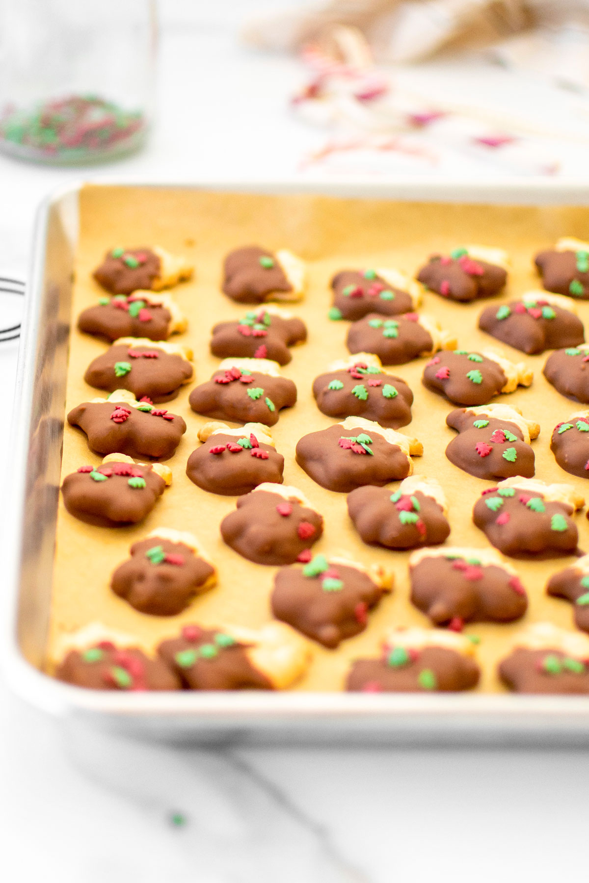 chocolate dipped animal crackers on a baking sheet on a white marble counter.